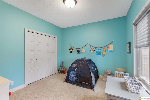 bedroom with carpet flooring, a closet, a textured ceiling, and baseboards