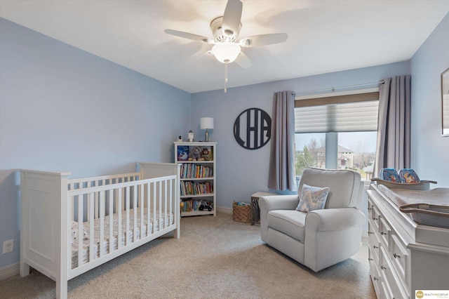 bedroom featuring a ceiling fan, baseboards, a crib, and carpet
