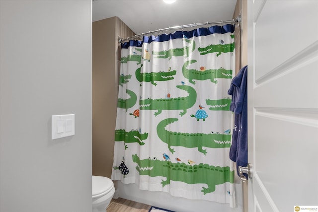 bathroom with toilet, shower / bath combo with shower curtain, and wood finished floors
