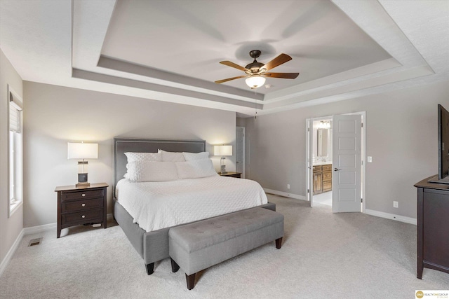 bedroom with baseboards, a tray ceiling, and light colored carpet