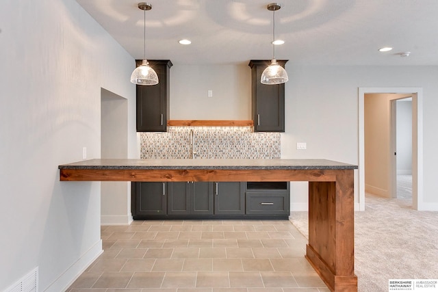 kitchen with tasteful backsplash, visible vents, light carpet, and baseboards