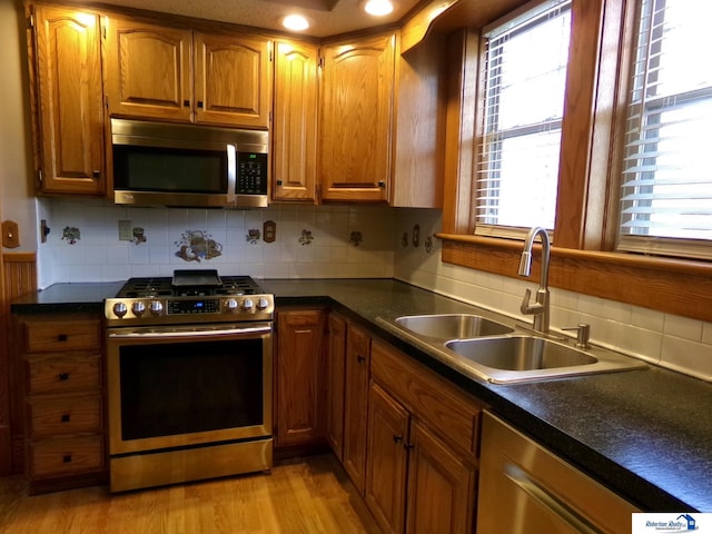 800 N 12th St, Beatrice, NE 68310 - kitchen featuring backsplash, light wood-style floors, brown cabinetry, stainless steel appliances, and a sink