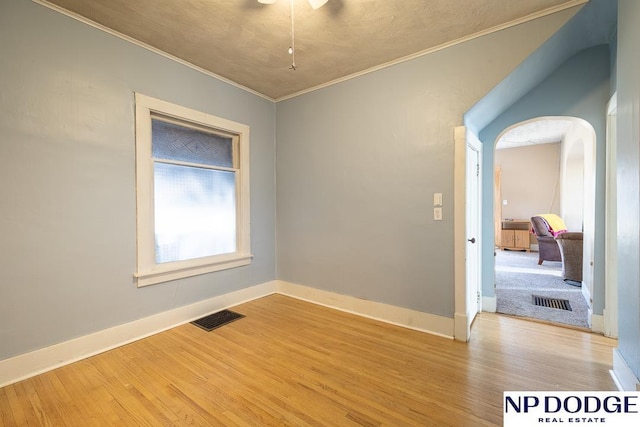 1042 Seward St, Seward, NE 68434 - unfurnished room featuring visible vents, crown molding, baseboards, wood finished floors, and arched walkways