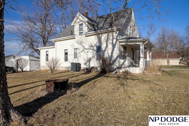 1042 Seward St, Seward, NE 68434 - view of side of home featuring roof with shingles, a yard, covered porch, central AC, and a chimney