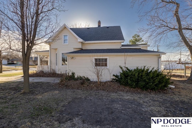 1042 Seward St, Seward, NE 68434 - view of side of property featuring a carport, roof with shingles, and a chimney
