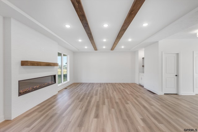 10907 N 167th St, Bennington, NE 68007 - unfurnished living room with beamed ceiling, light wood-type flooring, a glass covered fireplace, baseboards, and recessed lighting