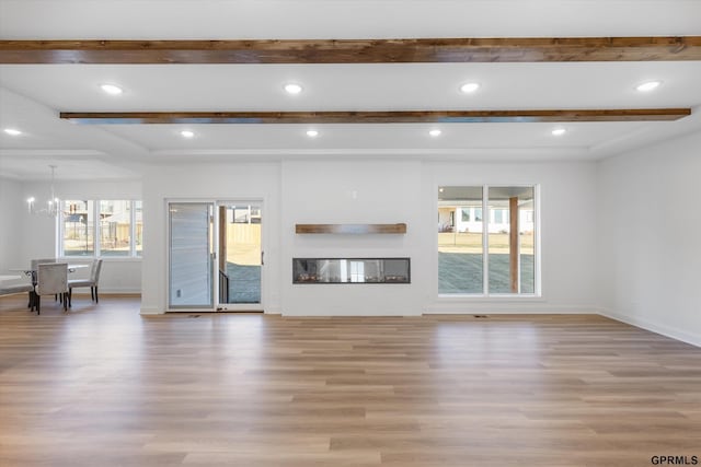 10907 N 167th St, Bennington, NE 68007 - unfurnished living room featuring light wood-style floors, beam ceiling, baseboards, a chandelier, and a glass covered fireplace