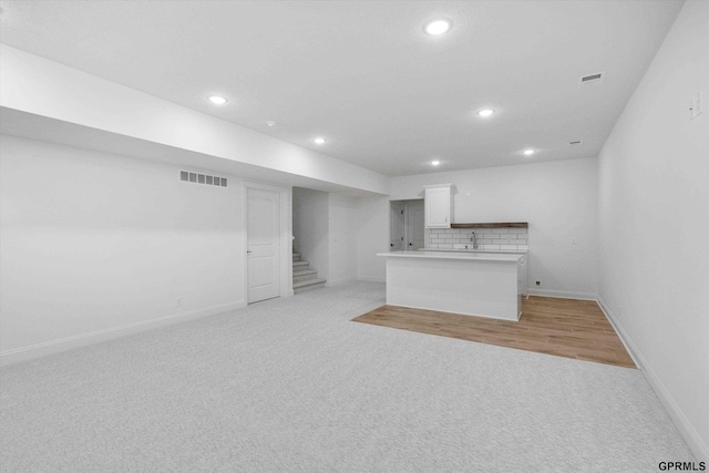 10907 N 167th St, Bennington, NE 68007 - unfurnished living room with light colored carpet, baseboards, wet bar, recessed lighting, and stairs