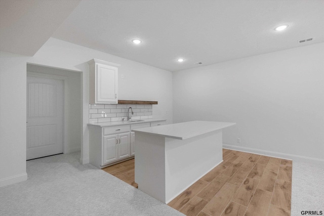 10907 N 167th St, Bennington, NE 68007 - kitchen with a sink, white cabinetry, light countertops, light wood-style flooring, and backsplash