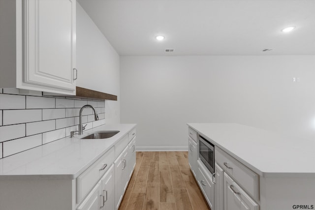 10907 N 167th St, Bennington, NE 68007 - kitchen with a sink, light countertops, stainless steel microwave, tasteful backsplash, and light wood-style flooring