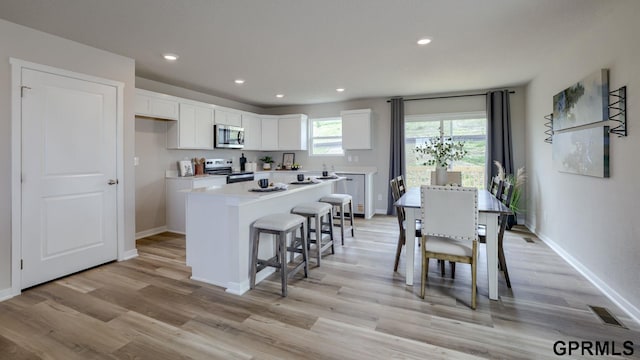 13607 Whitmore St, Omaha, NE 68142 - kitchen featuring appliances with stainless steel finishes, white cabinets, a center island, light wood-type flooring, and recessed lighting