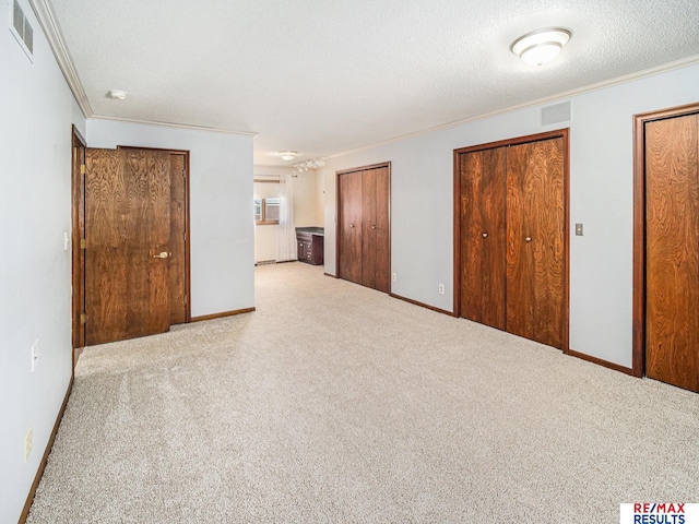 interior space with crown molding, visible vents, and multiple closets