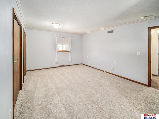 unfurnished bedroom featuring a textured ceiling, ornamental molding, visible vents, carpet floors, and baseboards