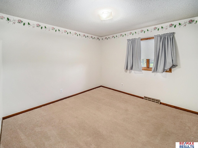 carpeted empty room featuring visible vents, baseboards, and a textured ceiling