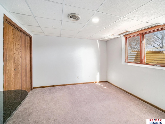 below grade area featuring visible vents, baseboards, a paneled ceiling, and carpet floors