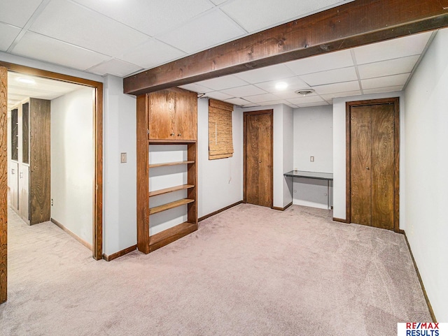 finished basement featuring light carpet, baseboards, and a drop ceiling