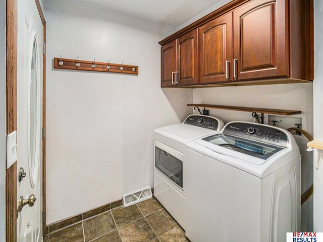 washroom with baseboards, washing machine and dryer, visible vents, cabinet space, and stone finish flooring