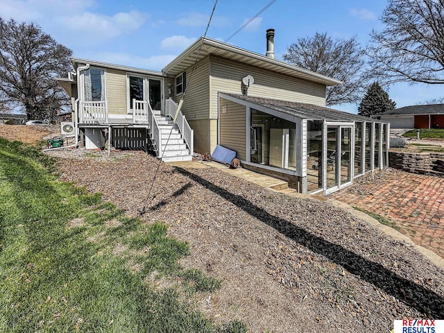 rear view of property with stairs and a sunroom