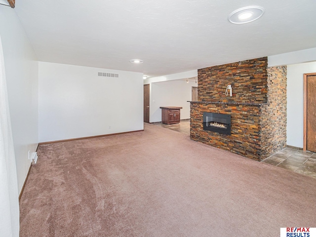 unfurnished living room featuring visible vents, carpet flooring, baseboards, and a stone fireplace
