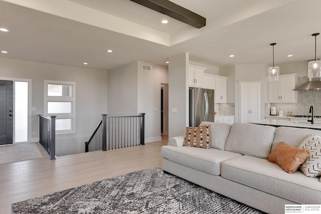 living room featuring baseboards, visible vents, light wood-style flooring, and recessed lighting