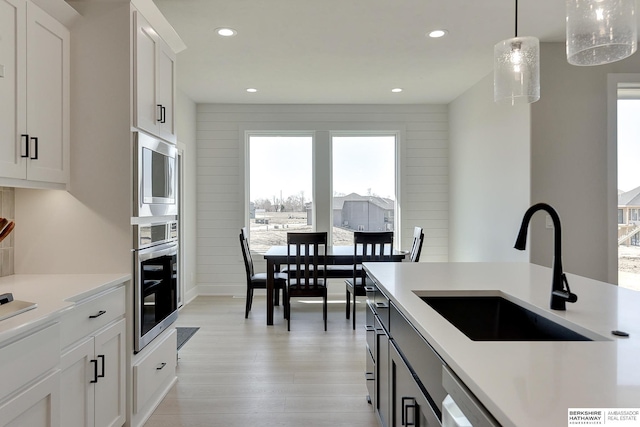 kitchen featuring light countertops, a sink, stainless steel appliances, and plenty of natural light