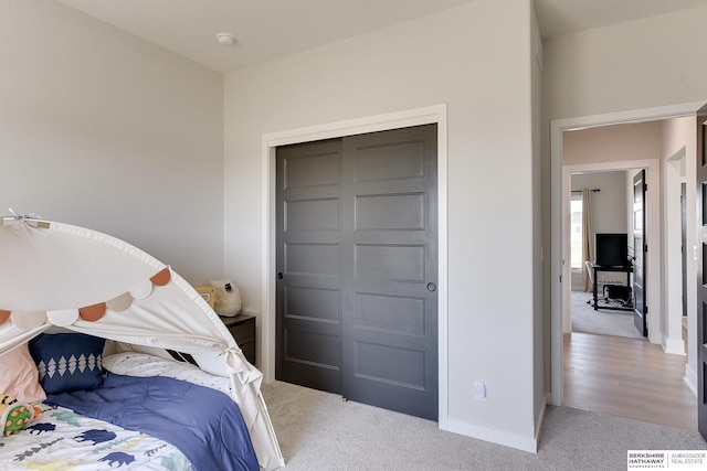 carpeted bedroom featuring baseboards and a closet