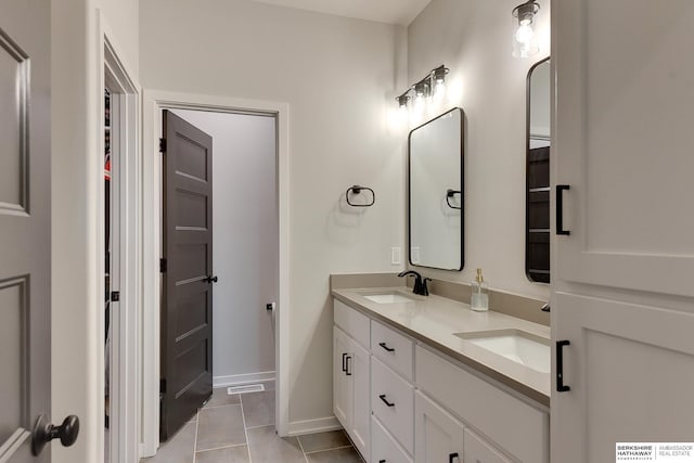 full bathroom featuring baseboards, double vanity, a sink, and tile patterned flooring