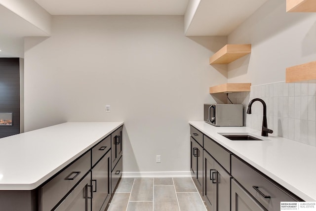 kitchen featuring a sink, light countertops, stainless steel microwave, and open shelves