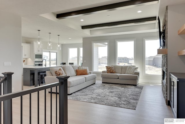 living area with beam ceiling, baseboards, light wood finished floors, and recessed lighting
