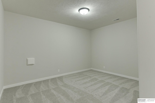 spare room featuring baseboards, visible vents, carpet flooring, and a textured ceiling