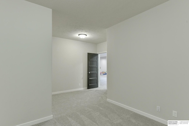 empty room featuring baseboards, a textured ceiling, and light carpet