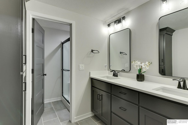 bathroom with double vanity, a sink, tile patterned flooring, and a shower stall