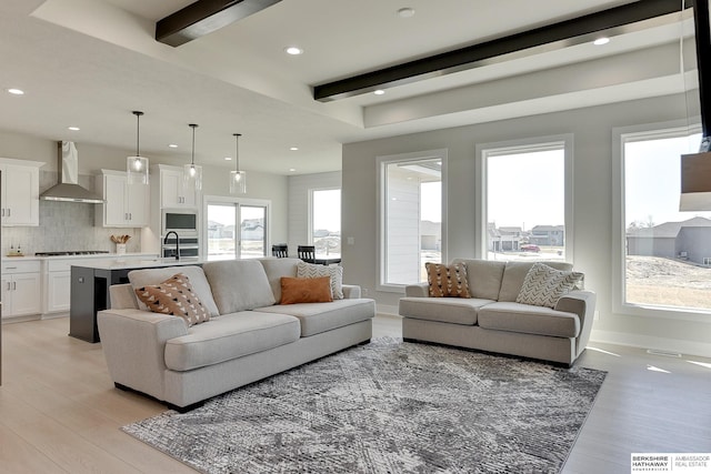living area with baseboards, light wood-type flooring, beam ceiling, and recessed lighting