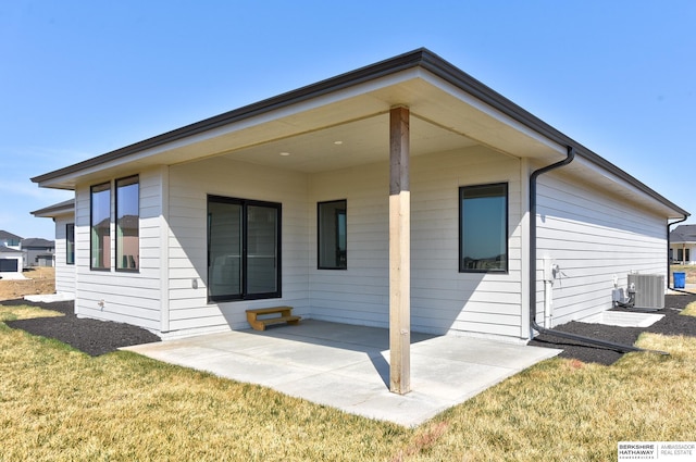 back of house with central AC unit, a lawn, and a patio area