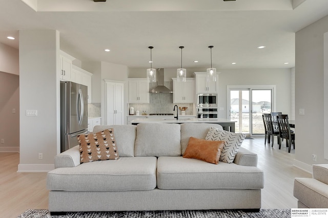 living room featuring baseboards, light wood finished floors, and recessed lighting