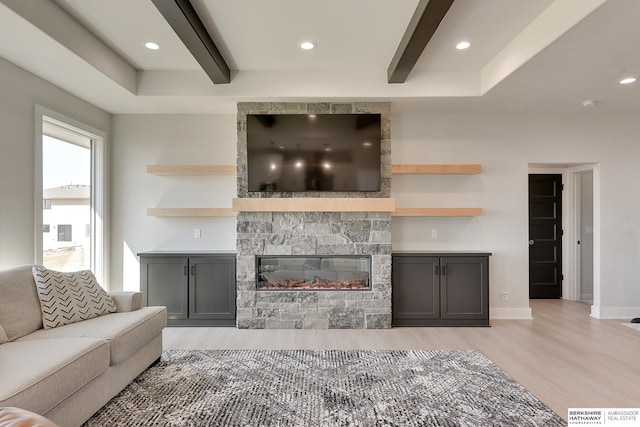 living area with beamed ceiling, light wood-style flooring, recessed lighting, and a fireplace