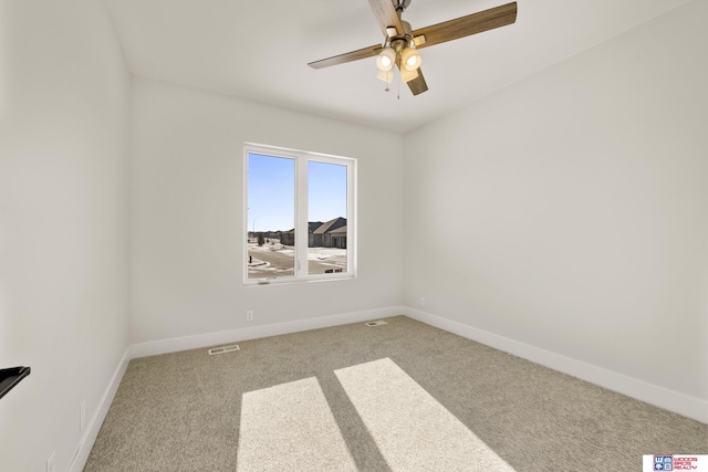 carpeted spare room featuring visible vents, baseboards, and ceiling fan