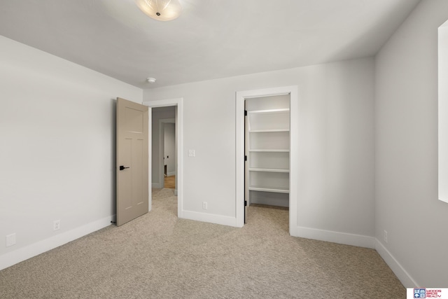 unfurnished bedroom featuring light carpet, baseboards, a closet, and a spacious closet