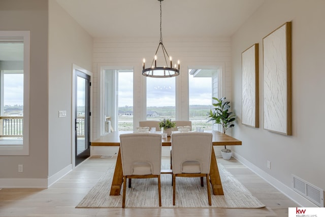 dining room featuring baseboards, visible vents, an inviting chandelier, and light wood-style floors