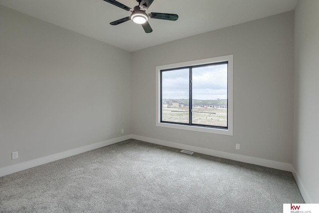 carpeted empty room featuring baseboards, visible vents, and ceiling fan