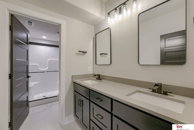bathroom with double vanity, visible vents, a shower stall, and a sink