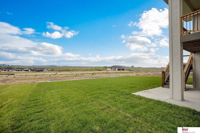 view of yard with stairway, a patio, and a rural view