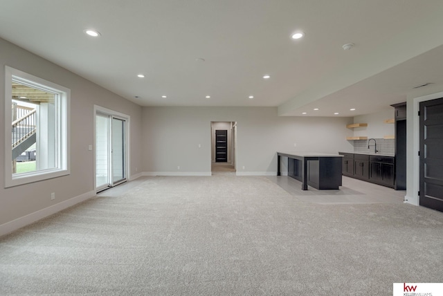 unfurnished living room featuring light colored carpet, a sink, baseboards, indoor wet bar, and recessed lighting