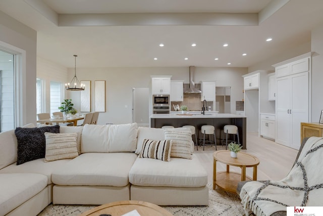 living room featuring recessed lighting, light wood-style floors, and a notable chandelier