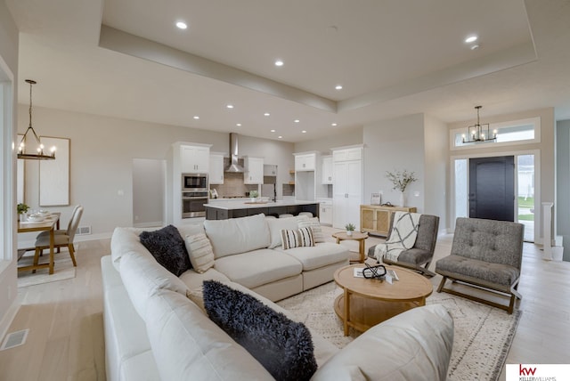 living area with visible vents, a notable chandelier, recessed lighting, and a raised ceiling