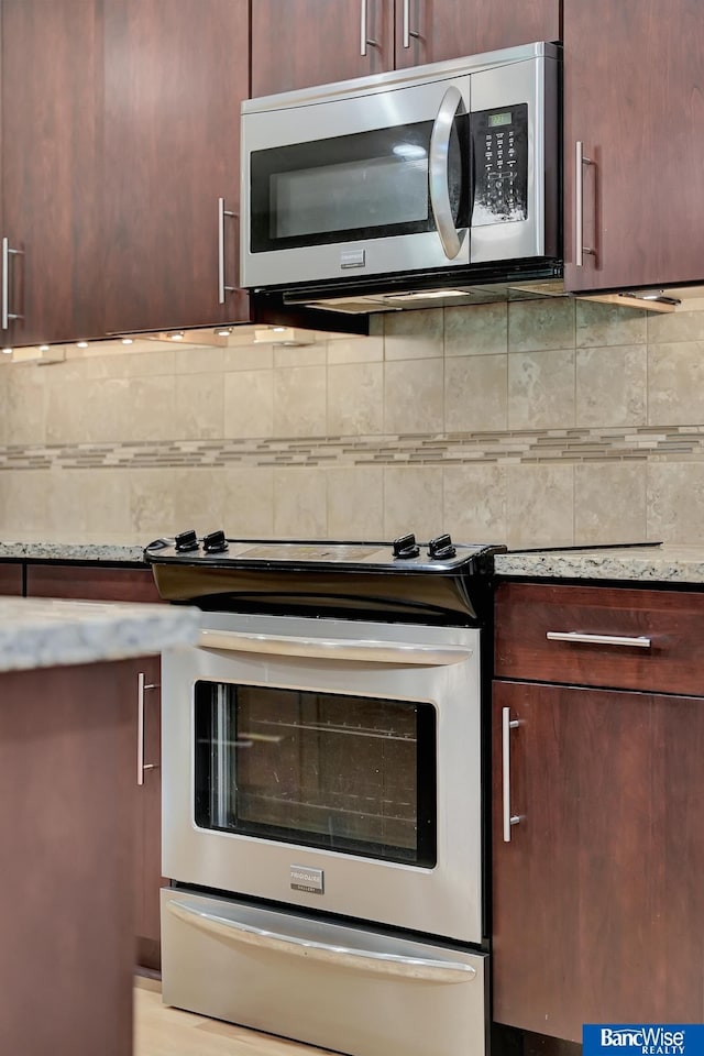 kitchen featuring dark brown cabinetry, stainless steel appliances, backsplash, and light stone counters