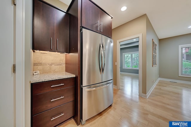 kitchen with stainless steel fridge, dark brown cabinets, tasteful backsplash, and light wood finished floors