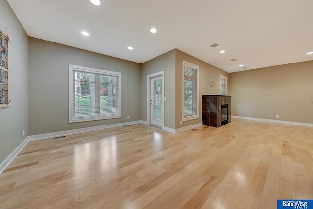unfurnished living room with visible vents, baseboards, a fireplace, recessed lighting, and light wood-type flooring