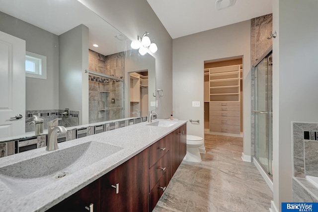 bathroom featuring a stall shower, double vanity, a spacious closet, and a sink