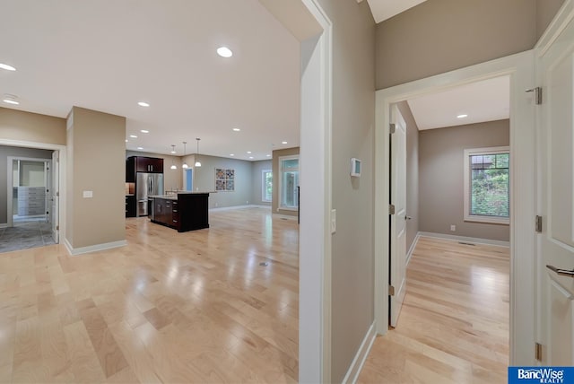 hall with baseboards, recessed lighting, and light wood-style floors